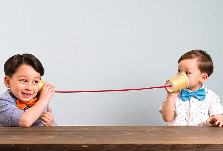 Two boys using string cup phones