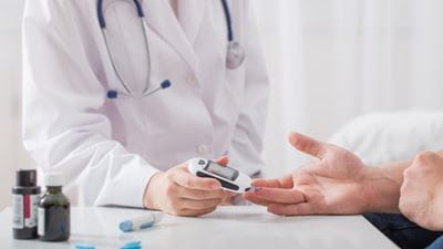 Doctor testing mans blood sugar