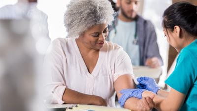 Nurse uses cotton swab on womans arm