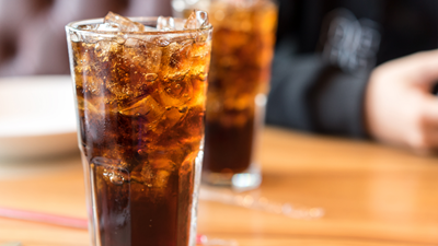 Two cups of iced cola sitting on a table.