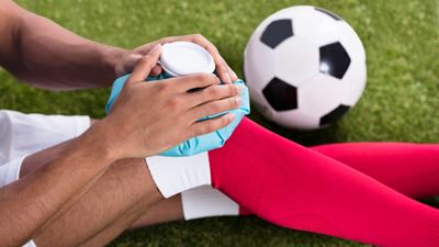 soccer player applying ice to a knee injury.