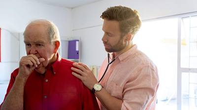 caucasian male doctor examining elderly patient