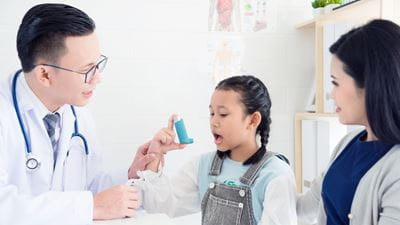 Doctor teaching girl to use inhaler