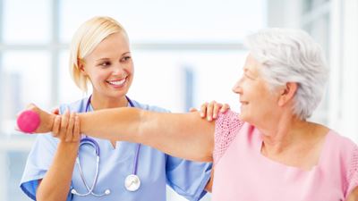 Female occupational therapist assisting elderly female patient