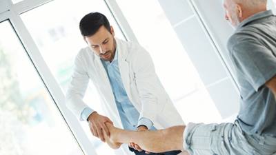 Male doctor examining male patients shin