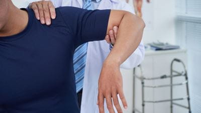 Physician examining male patients shoulder