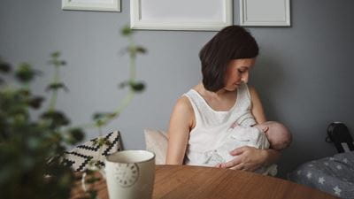 Woman breastfeeding baby at table