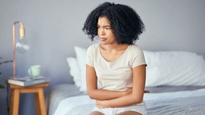 Woman holding stomach on bed