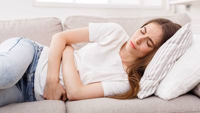 Woman laying on couch in pain