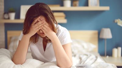 Woman sitting in bed feeling overhelmed