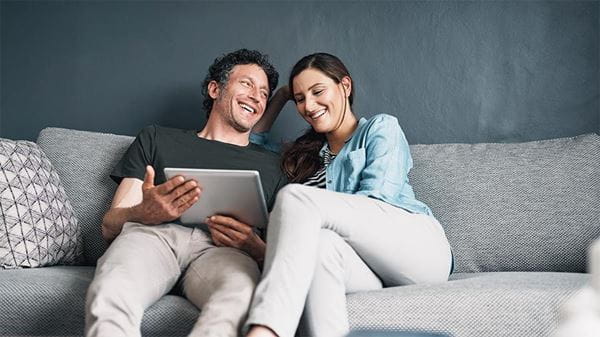 A couple using a digital tablet together while relaxing at home