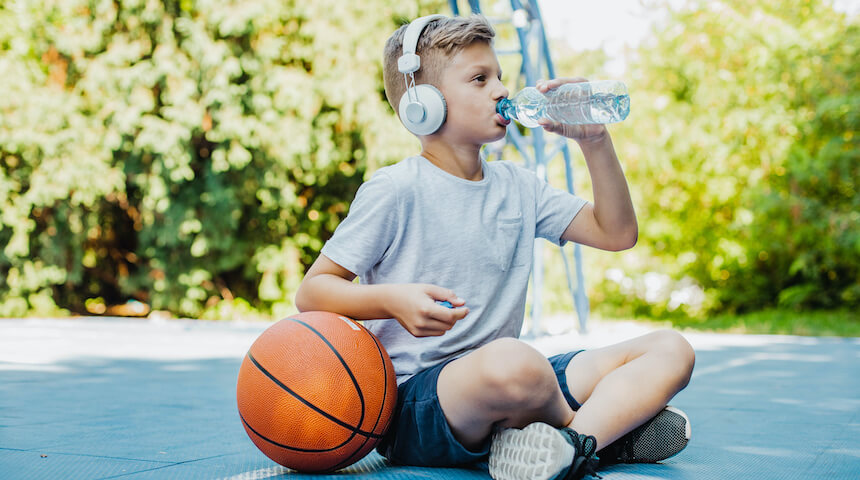 Boy with basketball drinking water