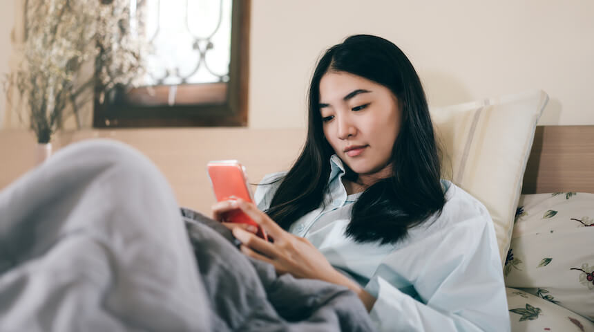 Woman laying in bed using her smart phone