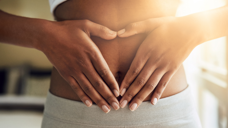 Woman is making a heart around her stomach using her hands 
