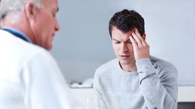 Male patient explaining headache to physician. 