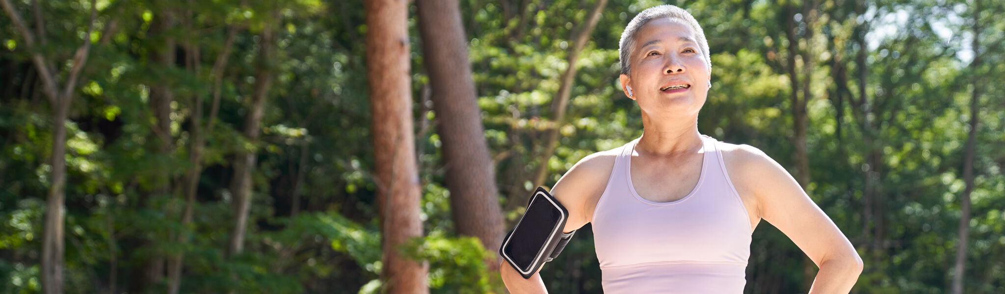 short-haired woman outside wearing tank top with phone strapped on arm
