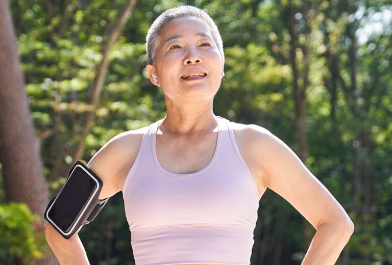 short-haired woman outside wearing tank top with phone strapped on arm