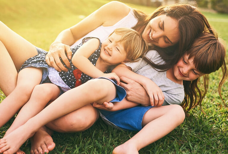 Mother playing with children on grass
