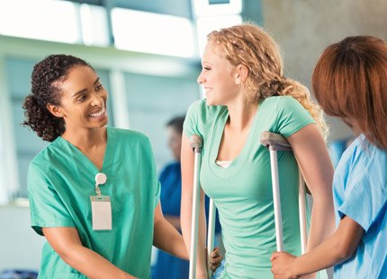 Physician helping girl on crutches