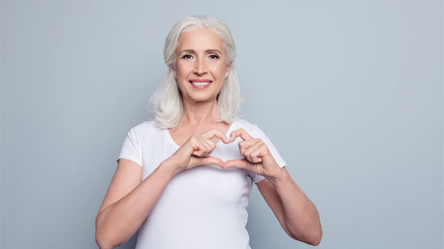 Female holding hands in shape of heart over chest