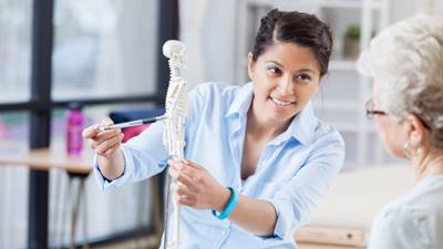 Female doctor pointing to bones on a skeleton model