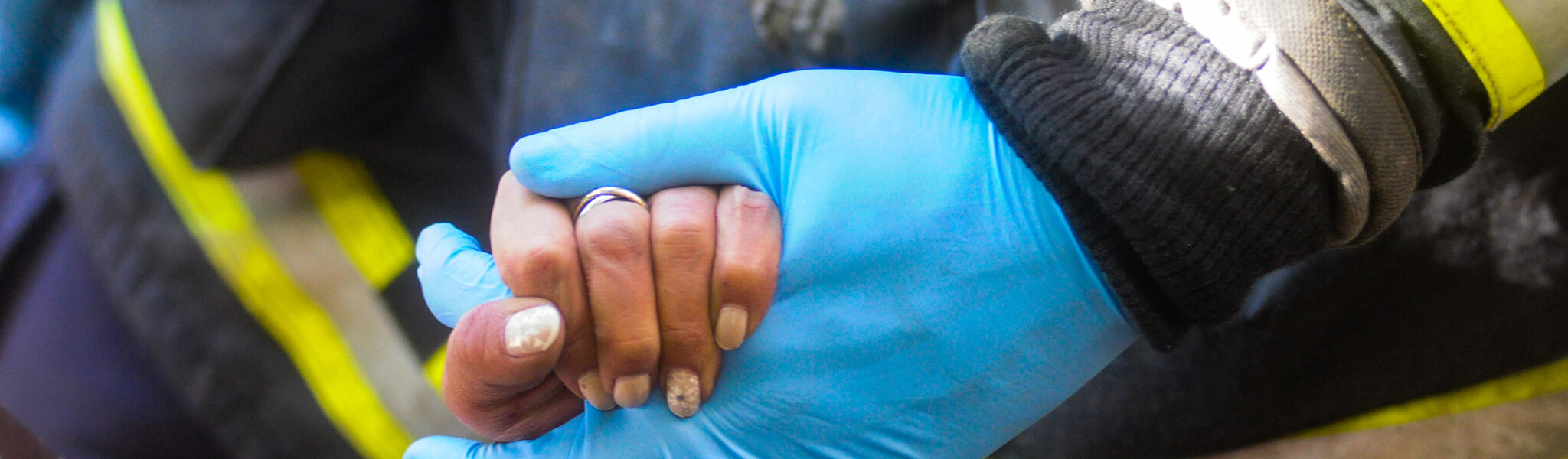 Hand holding blue gloved hand