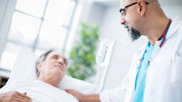 Doctor speaking to man in hospital bed