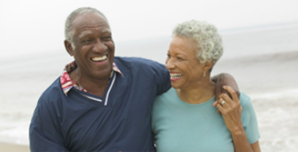 Older couple happily walking along beach.