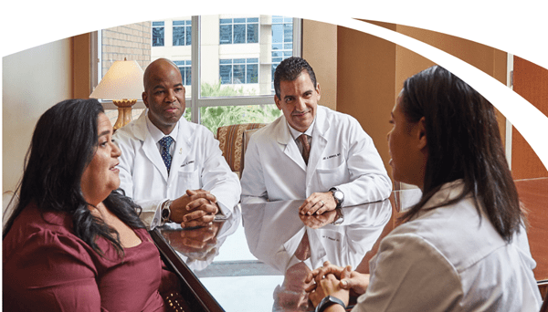 Team of physicians sitting with patient around a table discussing lung cancer diagnosis.