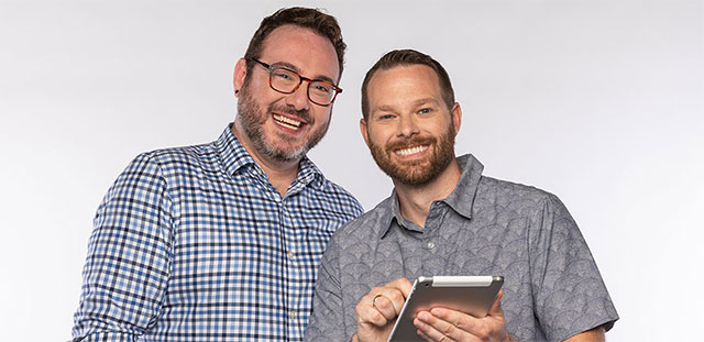 Male couple smiling holding tablet
