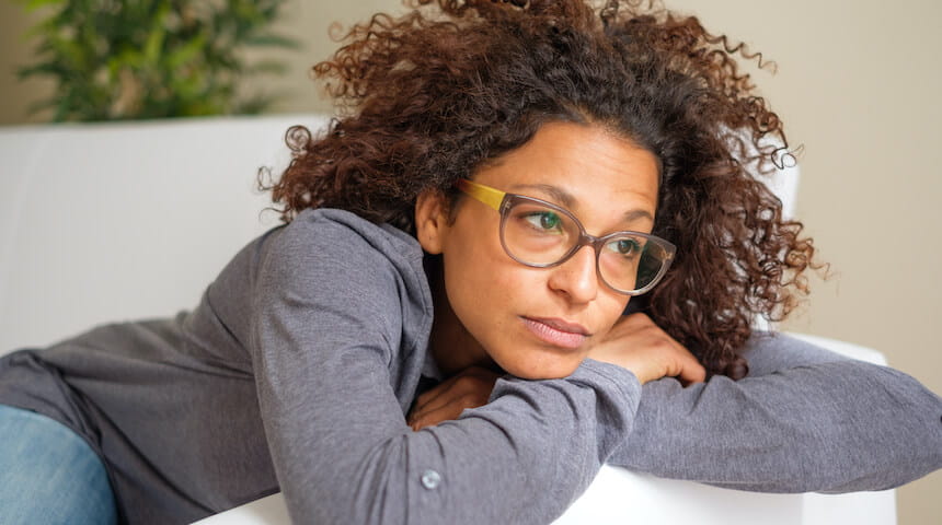 Tired woman leaning on couch arm 