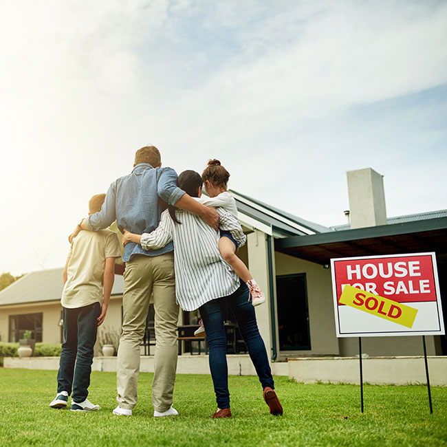 Family hugging outside of sold house
