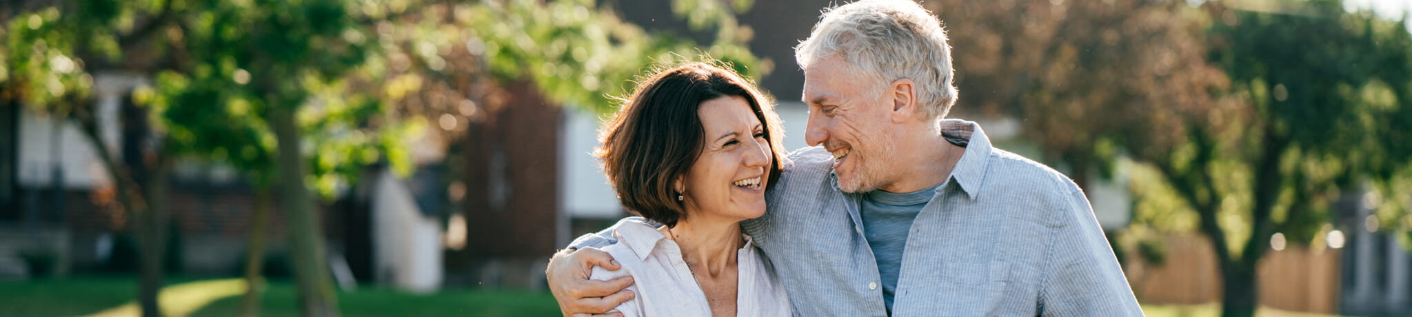 Couple smiling at each other with arm wrapped around shoulder