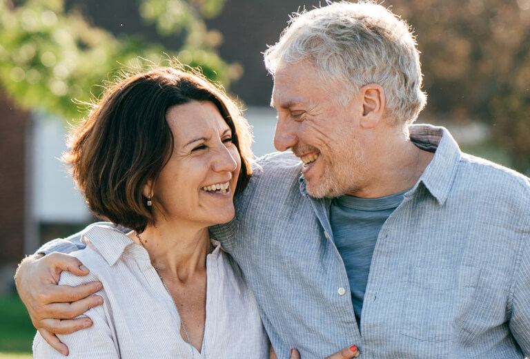 Couple smiling at each other with arm wrapped around shoulder