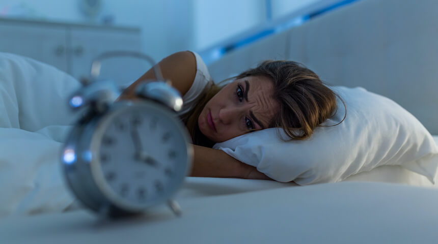 Woman trying to sleep staring at alarm clock