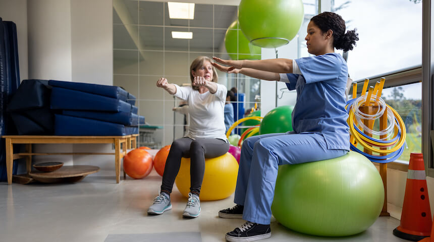 A woman and physical therapist sitting on exercise balls