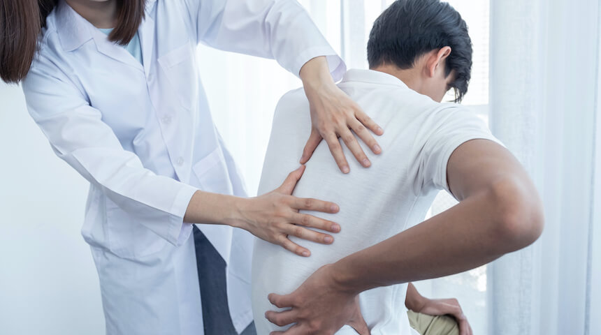 Doctor examining man with back pain