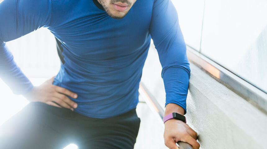 Man with hip injury holding hip and wall railing