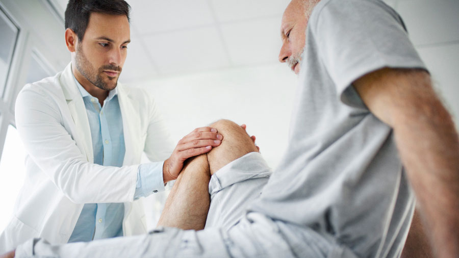 Male physician examining patients leg