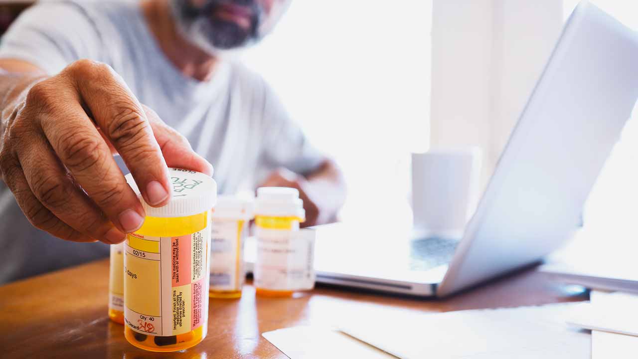 man looking at pill bottles