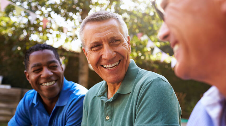 three men smiling at each other outside wearing polos