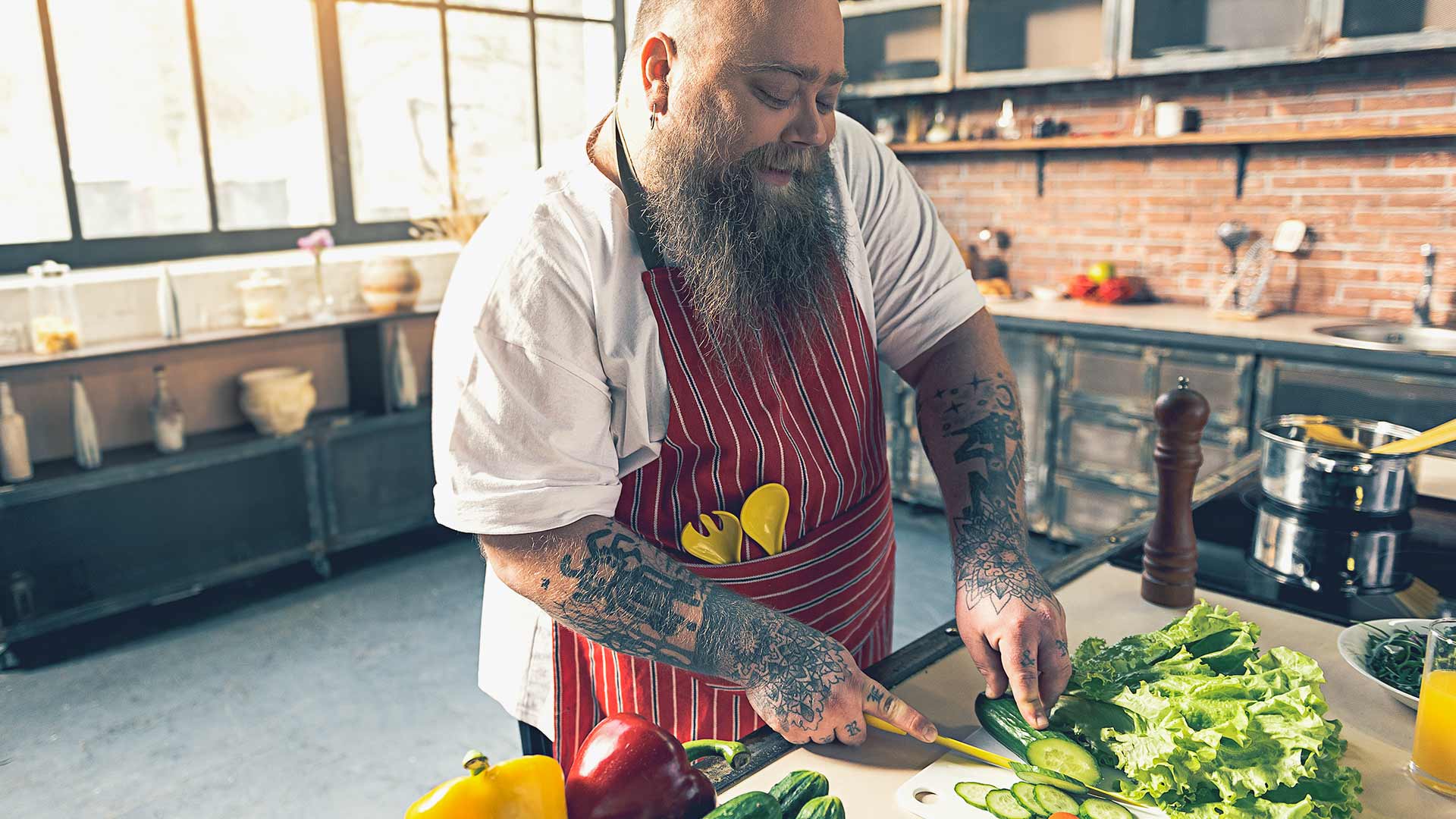 Overweight man is enjoying cooking vegetable in kitchen