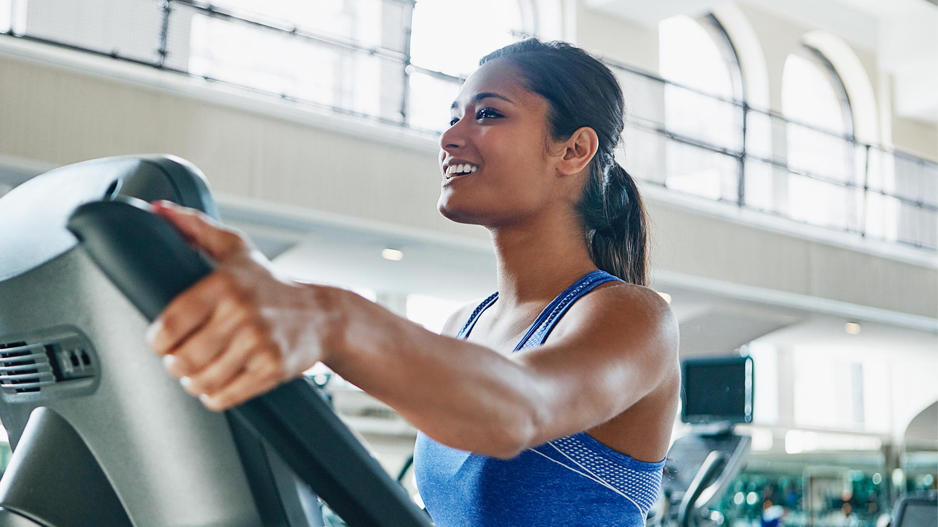 Young woman working out with an elliptical machine at a gym