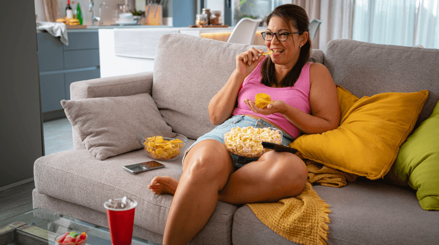 Lady sitting on couch eating snacks