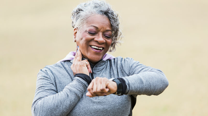 Woman touching neck checking heart rate and looking at wrist watch