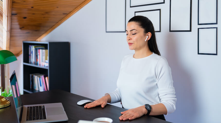 Woman standing in front of computer with eyes closed