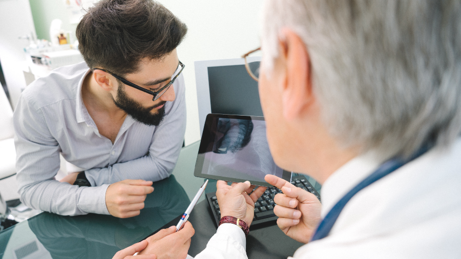 Physician showing patient x-ray of lungs on an iPad.