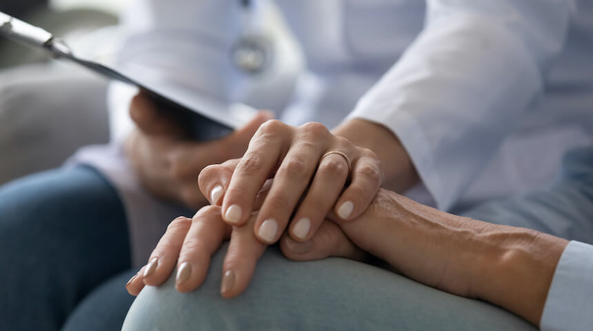 doctor's hand on top of patient's hands