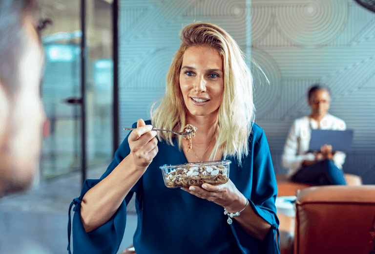 Woman sitting with a fork full of food and glass container