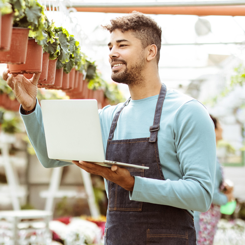 man with apron holding a laptop